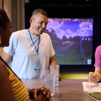 Friends laughing in a TopGolf Swing Suites Simulator at Tee Off at The Wharf