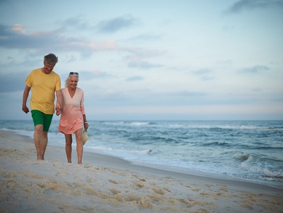 Snowbird couple walking along the shore in Orange Beach