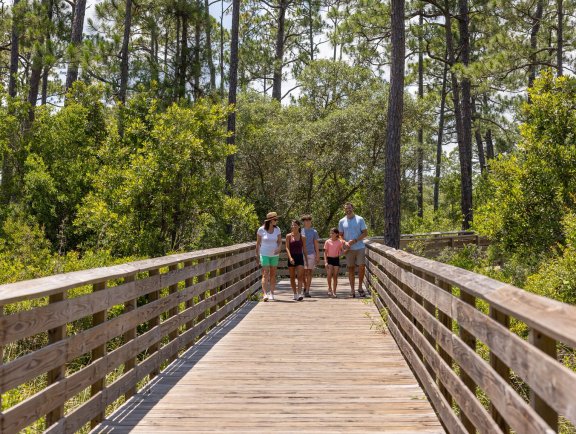 Family walking along a boardwalk on the Hugh S. Branyon Backcountry Trail in Gulf State Park