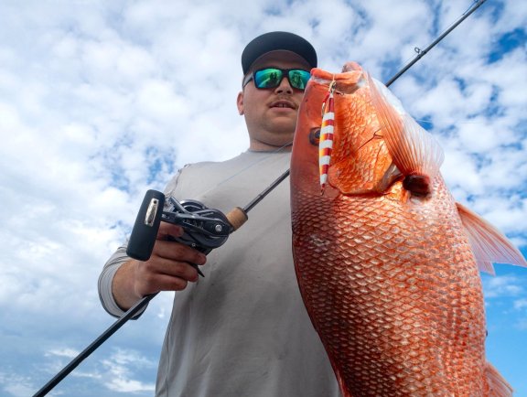 Angler holding a red snapper caught on a fishing charter in Orange Beach
