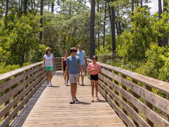 family walking along boardwalk trail in gulf state park