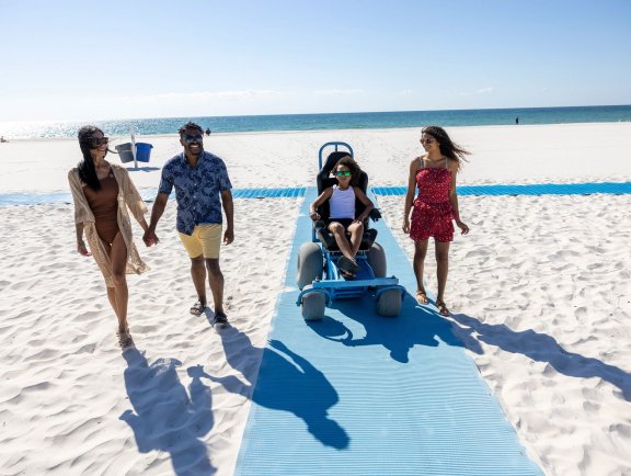 Family using the wheelchair accessible beach mat at the beach in gulf shores