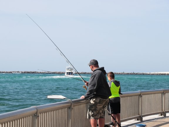 Dad and son fishing in the Gulf at Perdido Pass Seawall Park in Orange Beach
