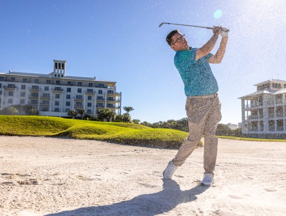 Golfer hitting a ball out of a sand bunker at Kiva Dunes