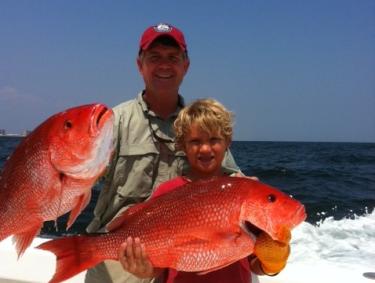 Father and son holding red snapper