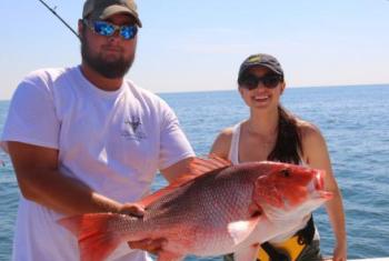 Couple holding catch on charter fishing boat in Orange Beach