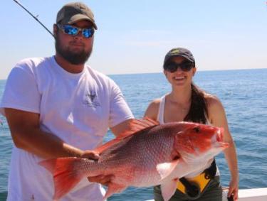 Couple holding catch on charter fishing boat in Orange Beach