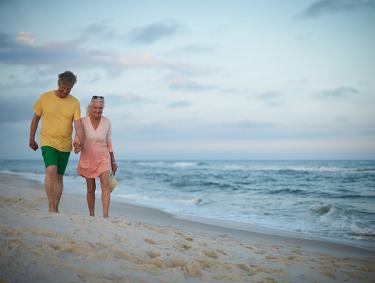 Snowbird couple walking along the shore in Orange Beach