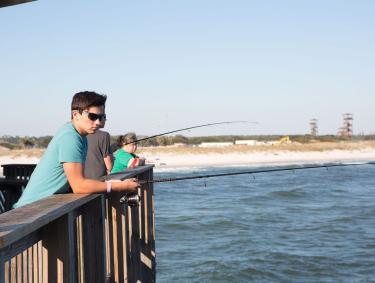 Teen boy fishing off the Gulf State Park Pier in Gulf Shores, AL