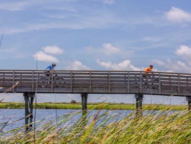 People biking on a boardwalk across Lake Shelby in Gulf State Park