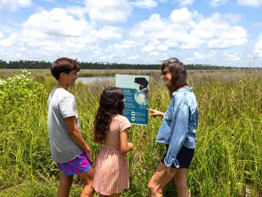 Family reading a sign inside Gulf State Park
