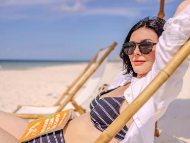 Woman sitting in a beach chair with a book in her lap on the beach in Gulf Shores