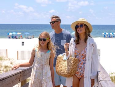 Family walking along a boardwalk on the beach in Gulf Shores
