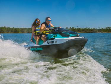 Couple riding a Jet Ski across the water in Orange Beach