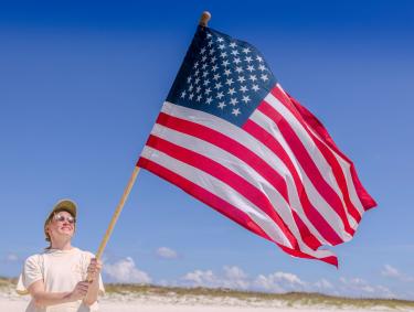 Woman holding an American flag on the beach in Orange Beach