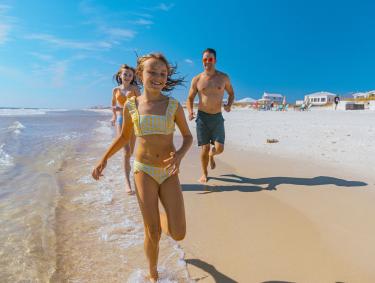 Family running along the water on the beach in Gulf Shores