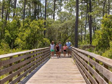 Family walking along a boardwalk on the Hugh S. Branyon Backcountry Trail in Gulf State Park