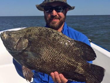 angler holding a tripletail caught while fishing in Orange Beach