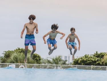 boys jumping into pool at The Caribe Resort in Orange Beach