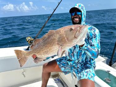 Angler holding a gag grouper caught on a fishing charter in Orange Beach