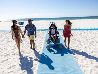 Family using the wheelchair accessible beach mat at the beach in gulf shores