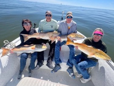 people on a fishing charter holding up redfish caught while inshore fishing in orange beach