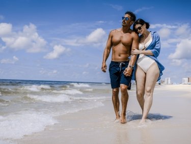 Couple walking arm in arm along the shoreline in Orange Beach