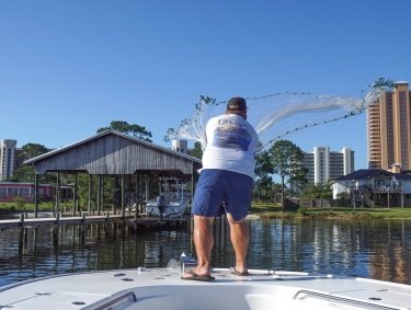 Angler casting a net into the back bays for bait