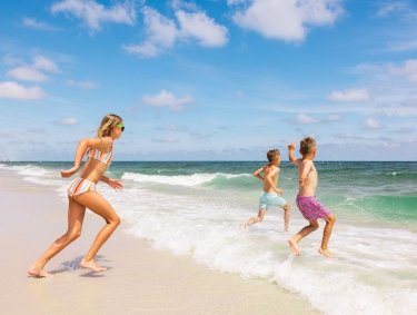 Kids running into the water at the beach in Gulf Shores