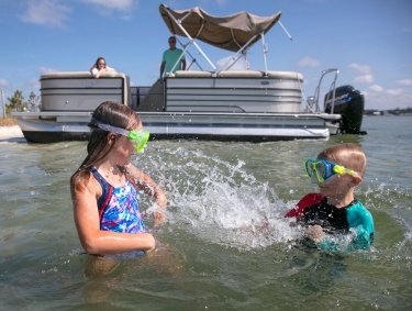 Kids splashing in the water by a pontoon boat rental in Orange Beach