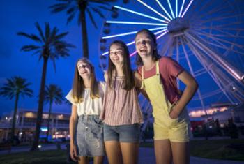girls in front the Ferris Wheel at The Wharf at night