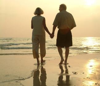Older couple walking on the beach holding hands