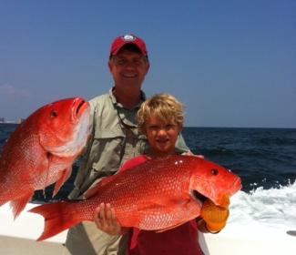Father and son holding red snapper