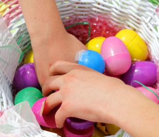 Hands reach for Easter Eggs in basket