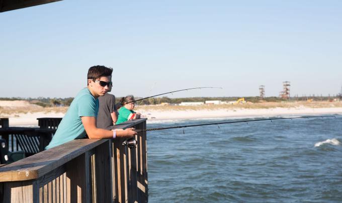 Teen boy fishing off the Gulf State Park Pier in Gulf Shores, AL