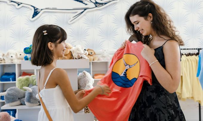 Two girls holding a t shirt at The Wharf Store in Orange Beach