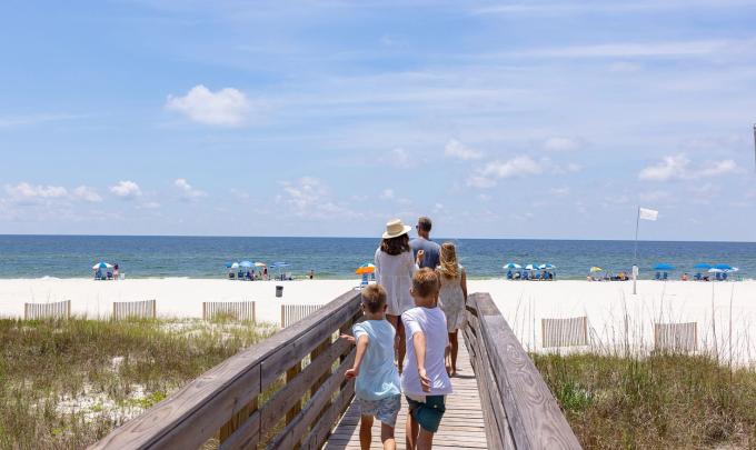 Family walking along a boardwalk towards the beach