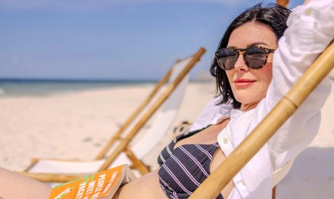 Woman sitting in a beach chair with a book in her lap on the beach in Gulf Shores