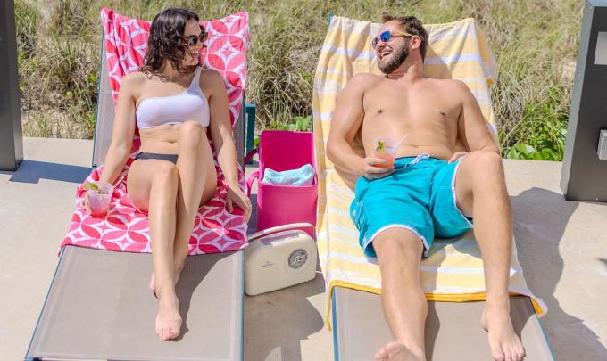 Couple lounging on chairs with cocktails by the pool at The Lodge