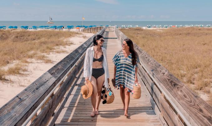 Two women walking on a boardwalk from the Gulf in Orange Beach