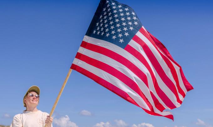 Woman holding an American flag on the beach in Orange Beach