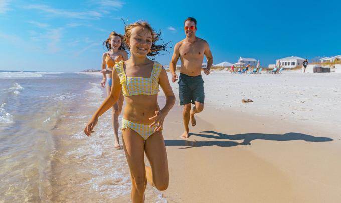 Family running along the water on the beach in Gulf Shores