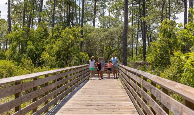 Family walking along a boardwalk on the Hugh S. Branyon Backcountry Trail in Gulf State Park