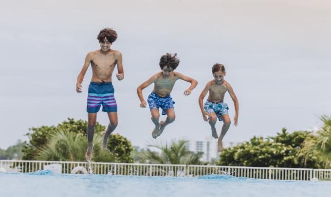 boys jumping into pool at The Caribe Resort in Orange Beach