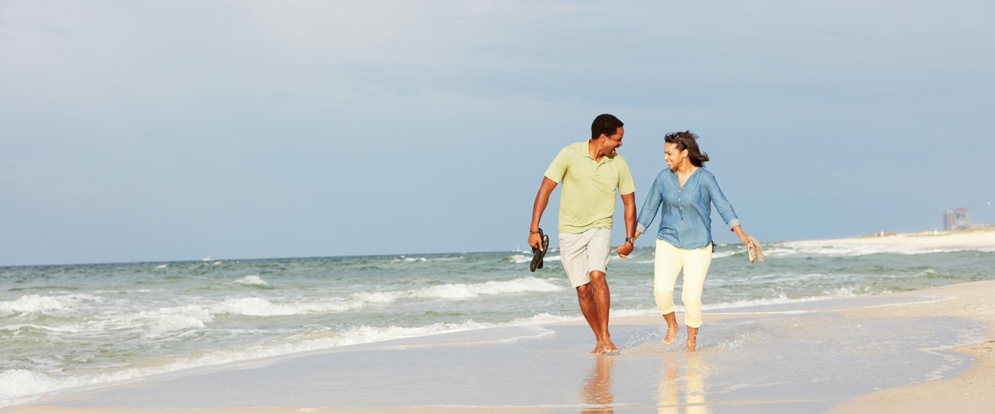 Couple walking on the beach holding hands laughing