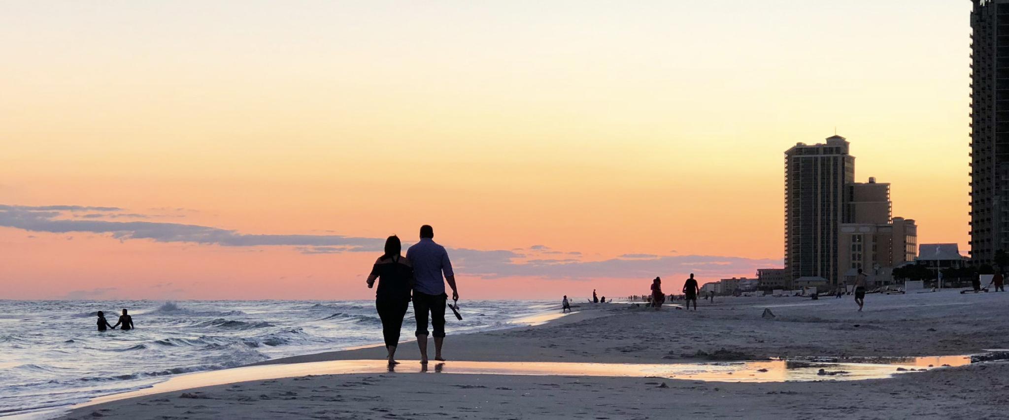 Couple walking on beach at sunset