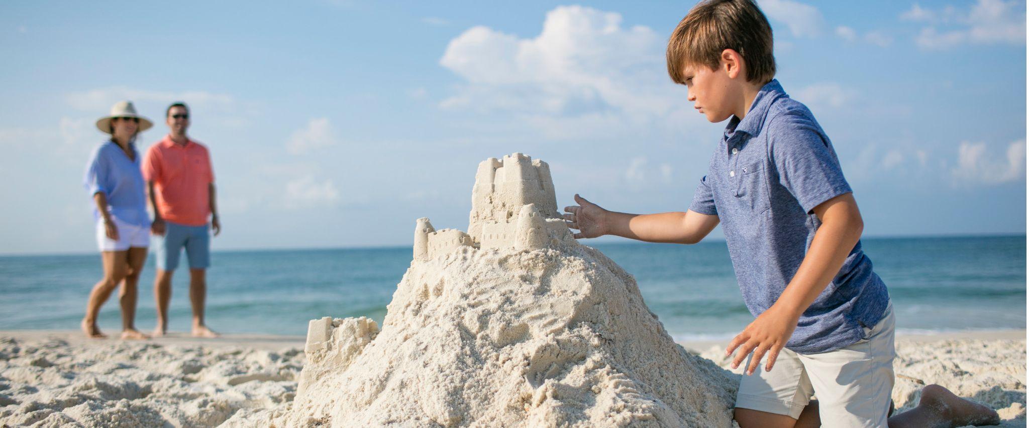 boy building sandcastle in orange beach