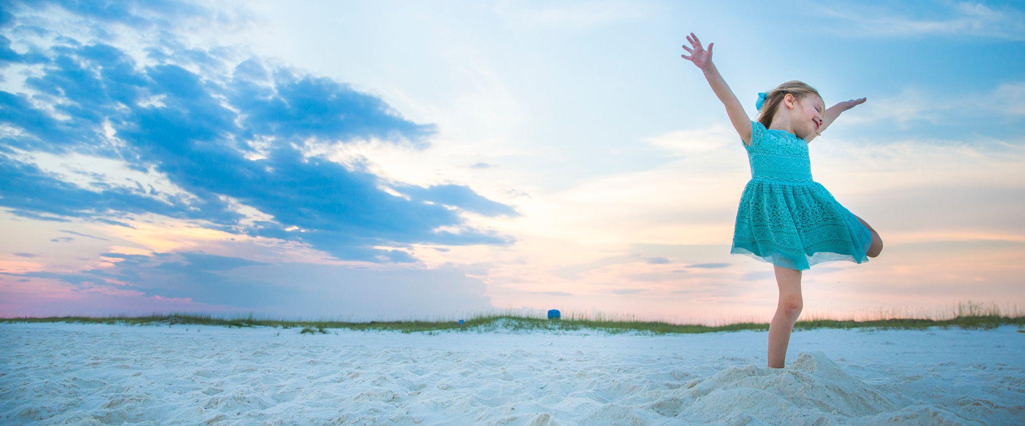 little girl jumping in the air on a beach in Orange Beach