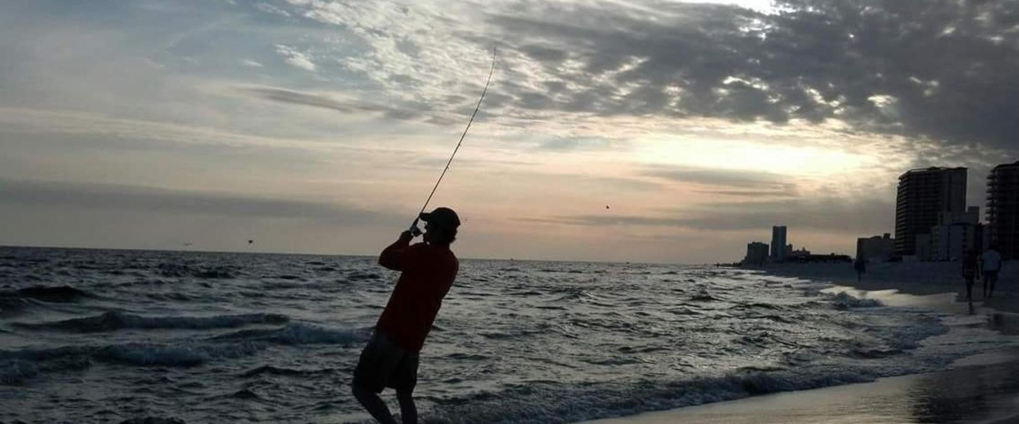 Man fishing on the beach in Alabama at sunset
