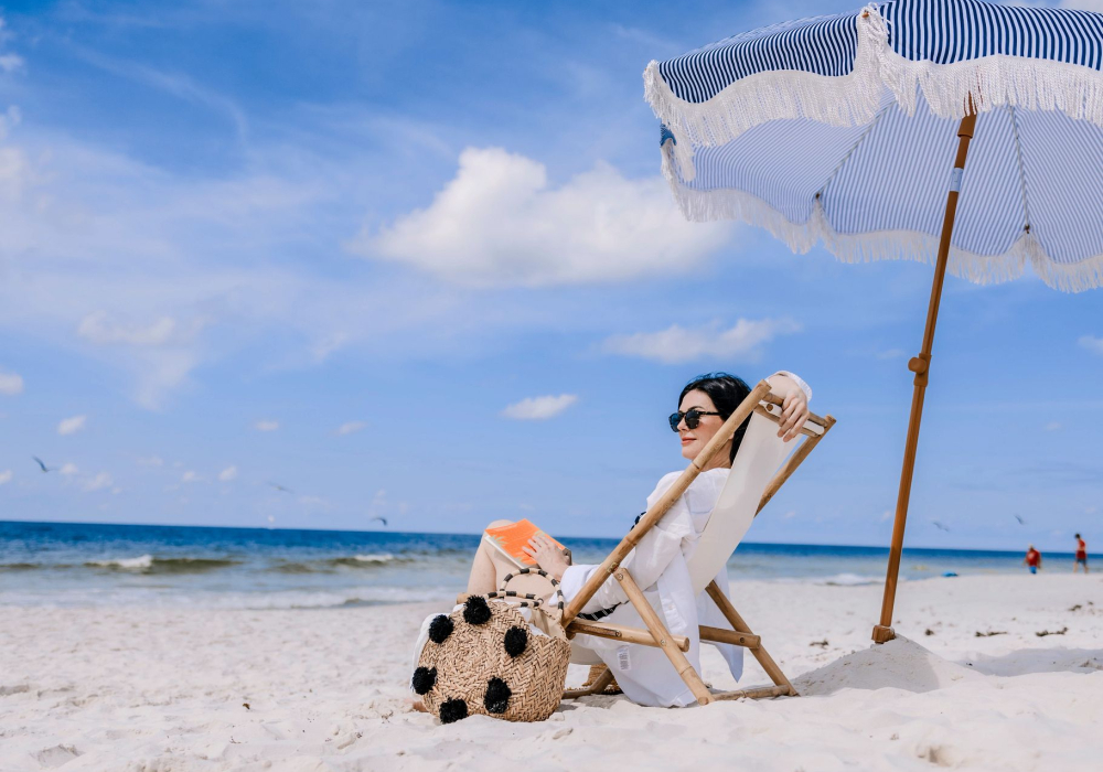 woman relaxing on the beach in a chair under an umbrella looking at the shore